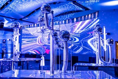 The space was also adorned with holographic projections of swirling galaxies, nebulae, and twinkling stars. The dance floor was a glowing, interactive LED surface that responded to the rhythm of the music, creating a kaleidoscope of colors that pulsed and shifted with the beat. YES Event Designs worked with Active Productions on AV and Wolfgang Puck Catering for the food.
