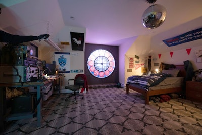 The Happy Death Day room resembled a quirky '80s-style dorm room filled with nostalgic decor, glitching digital clocks, and playful visual nods to the film's time-looping plot.