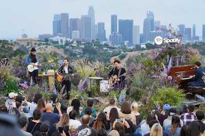 Spotify hosted a concert featuring Los Angeles-based band Local Natives in June 2019 at Angels Point at Elysian Park. Event designer Kim Swift created the event’s environment, adding wildflowers and greenery to the stage to make it look like the band was performing in a lush, naturally growing setting. Violet colors were inspired by the band’s album Violet Street.