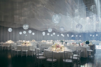 The wedding featured a ceiling treatment made from 3,000 feet of hand-cut fabric, juxtaposed with dozens of spherical crystal chandeliers.