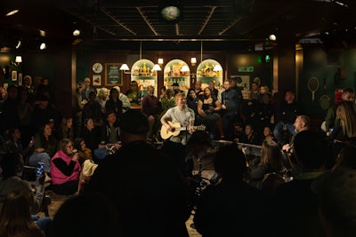 More than just a backdrop, the space—which had dark-green walls and leather booths for an authentic pub feel—was thoughtfully designed to function as a real working pub. Tiered seating offered views of the performance area, while the bar served as both a serving station and performance focal point. Interactive touches, like projected fan messages, kept guests engaged during both VIP and general admission events. Pink Sparrow worked with MKG on production.