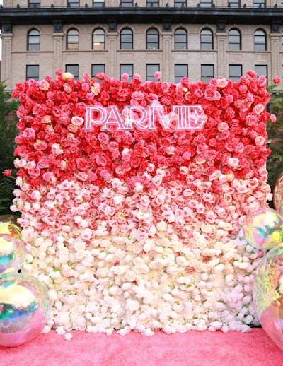 The step-and-repeat featured a backdrop with florals in gradients of pink.