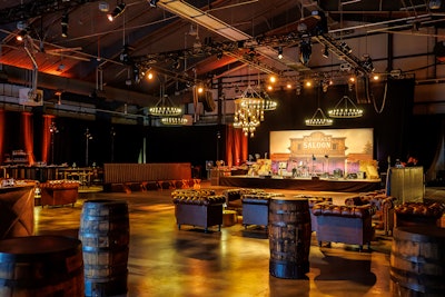 An oversize lantern installation hung over the dance floor, while 'Compass Saloon'-themed stage decor was flanked by hay bales. Stylish booth and lounge seating moments were available throughout the event, which featured a live band, a casino, and an assortment of Old West-inspired culinary experiences.
